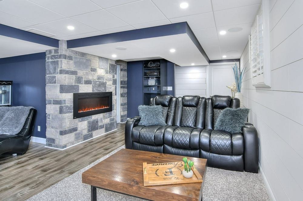 Finished media room with block-stone fireplace wall and black theater seating