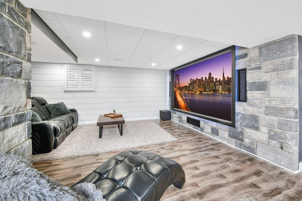 Wide finished media room with stone feature walls and projection screen