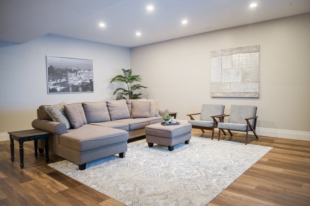 Finished lower-level sitting room with wood-look flooring and neutral furniture