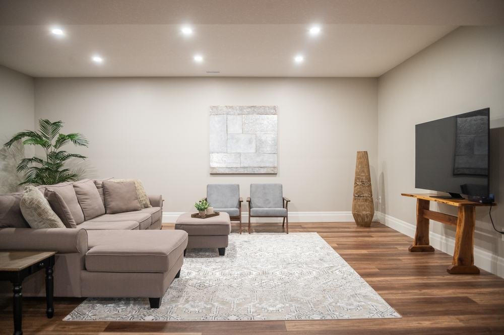 Finished lower-level sitting room with wood-look flooring and neutral seating