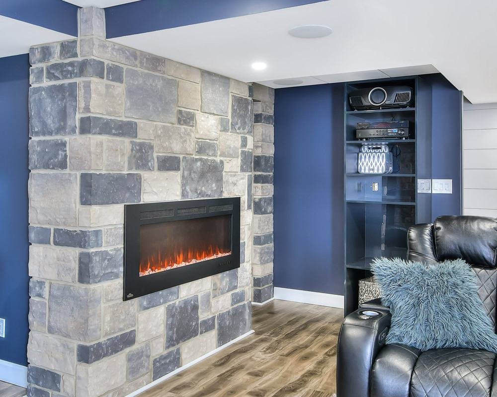 Linear fireplace set into a block-stone column in a blue lower-level media room