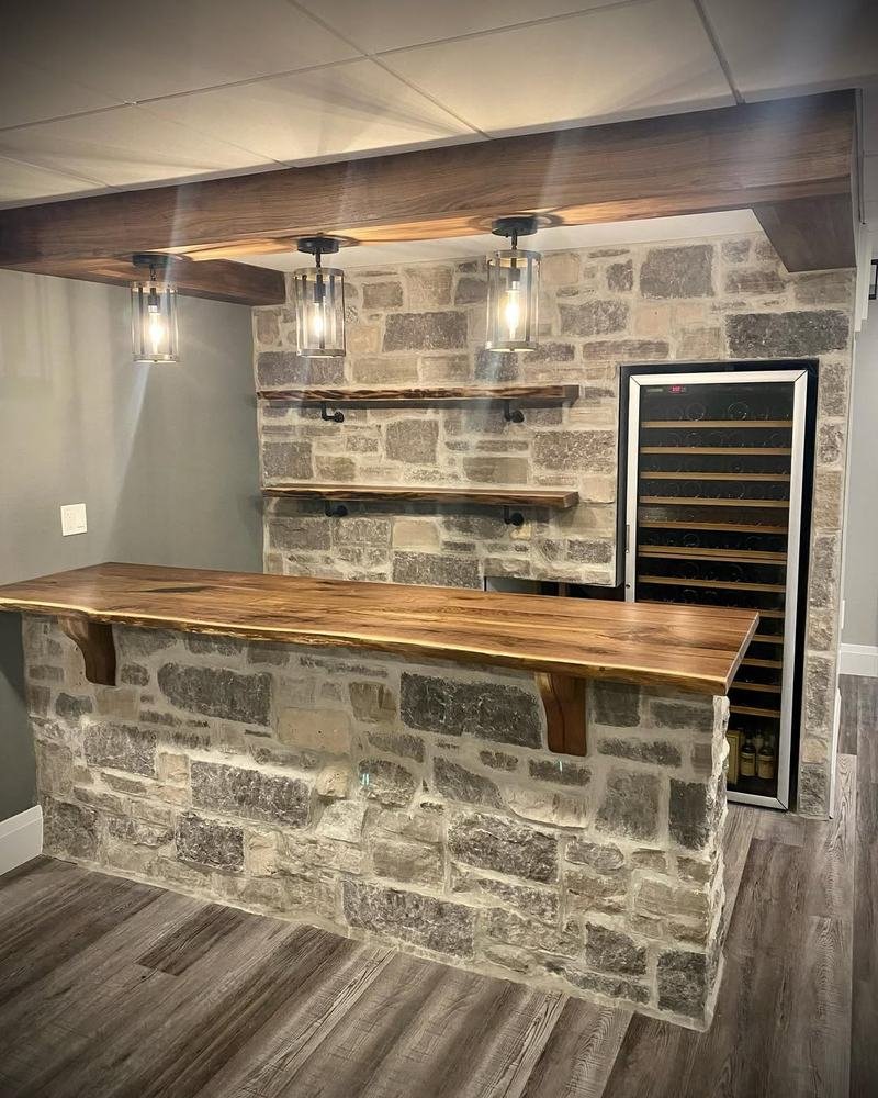 Basement bar with stone front, wood counter, shelving, and wine cooler