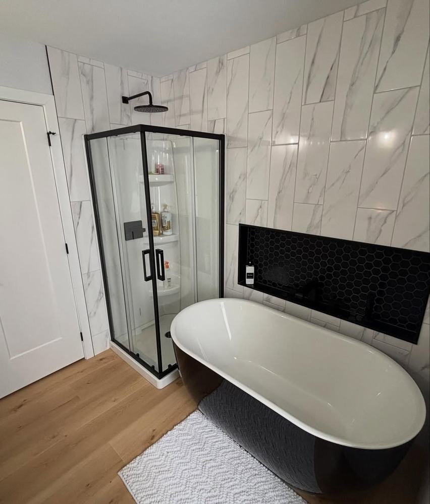 Finished bathroom with freestanding tub, glass shower, and large-format wall tile