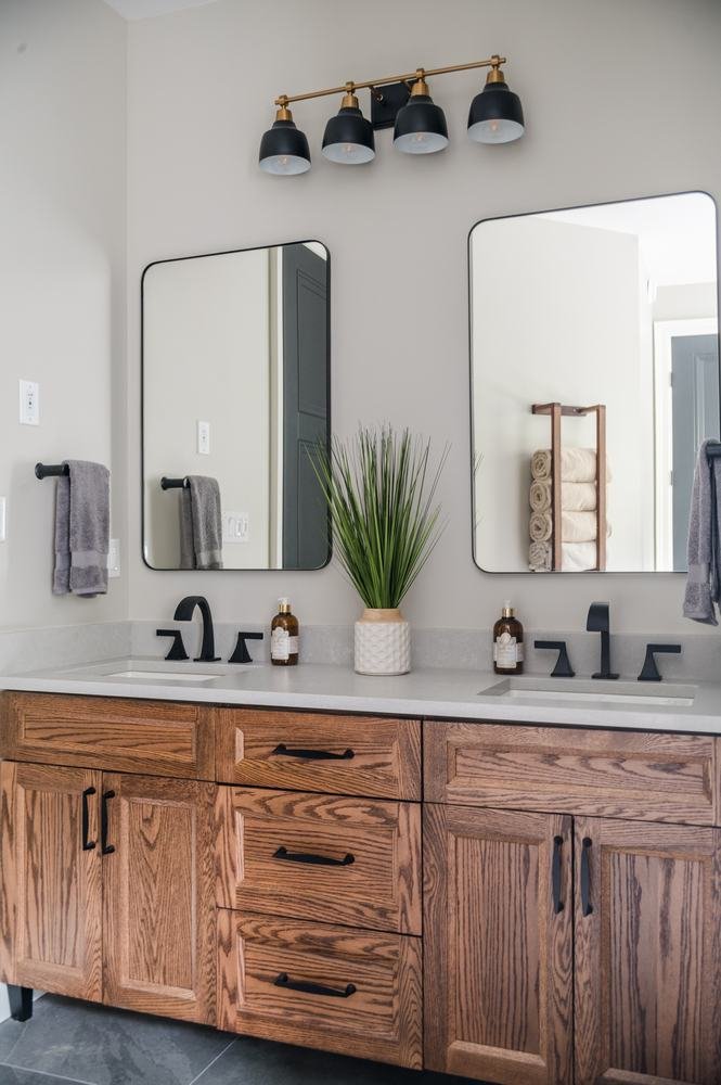 Double-sink wood vanity with mirrors and dark fixtures