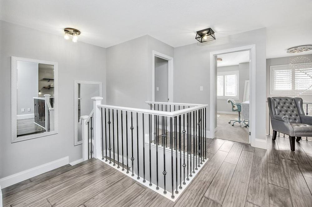 Bright upper landing with wood-look flooring and white-and-black railing