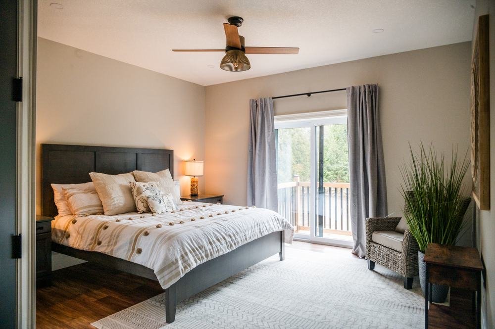 Finished bedroom with wood flooring, neutral decor, and a door to the deck