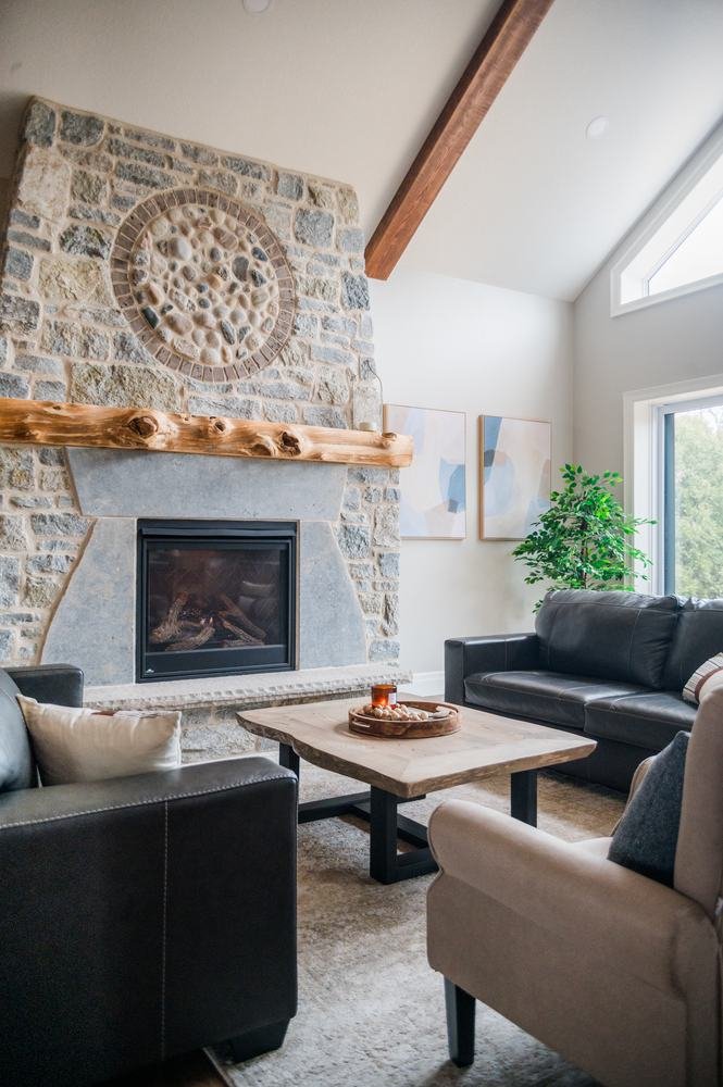 Living room centered on a rustic stone fireplace with circular medallion and log mantel