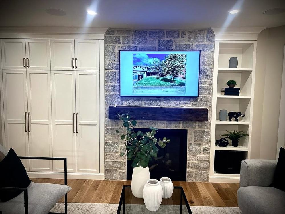 Traditional stone fireplace centered between tall white cabinets and shelving