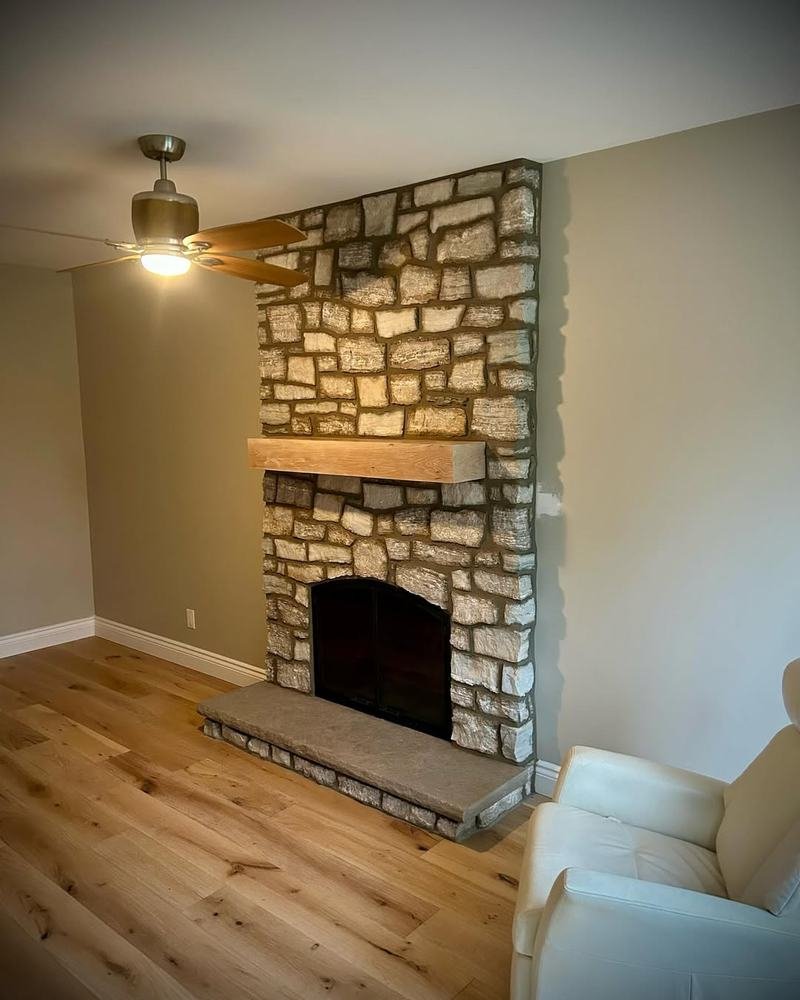 Natural-stone fireplace with wood mantel in a simple finished room