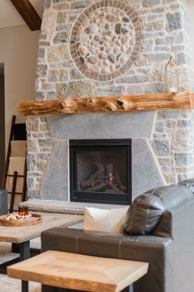 Rustic light-stone fireplace with circular stone medallion and log mantel