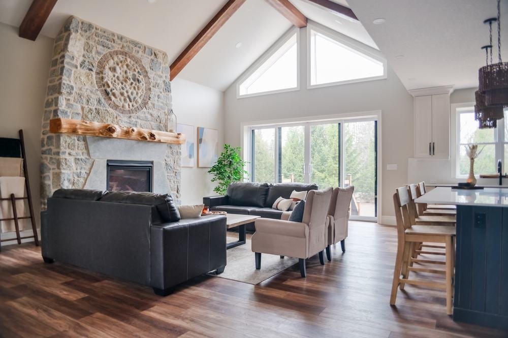 Open great room with stone fireplace, vaulted ceiling, and adjacent kitchen
