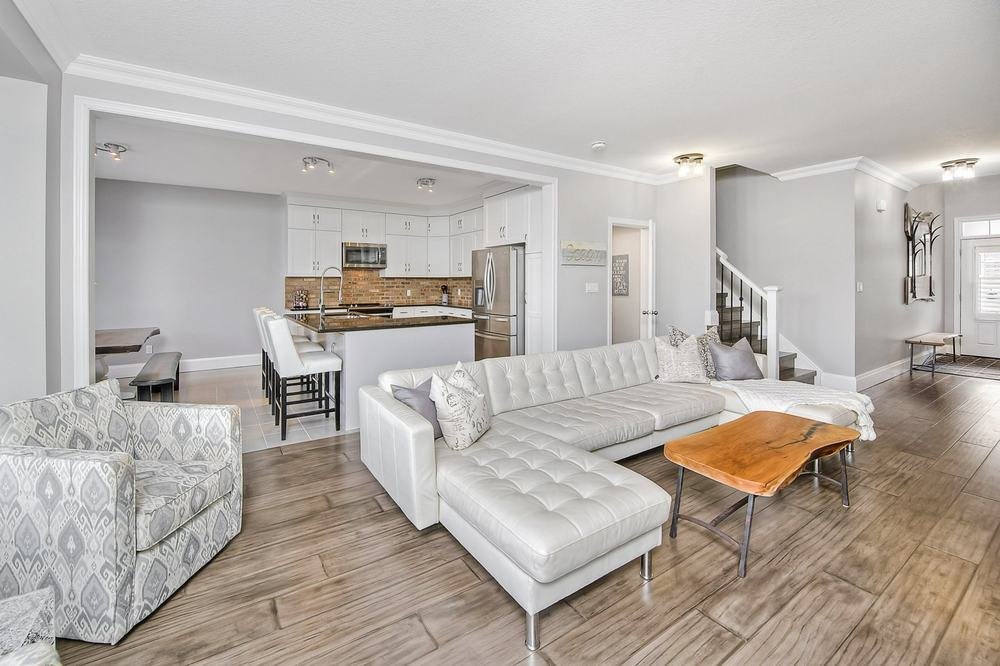 Wide open-plan living room looking toward a white kitchen and staircase