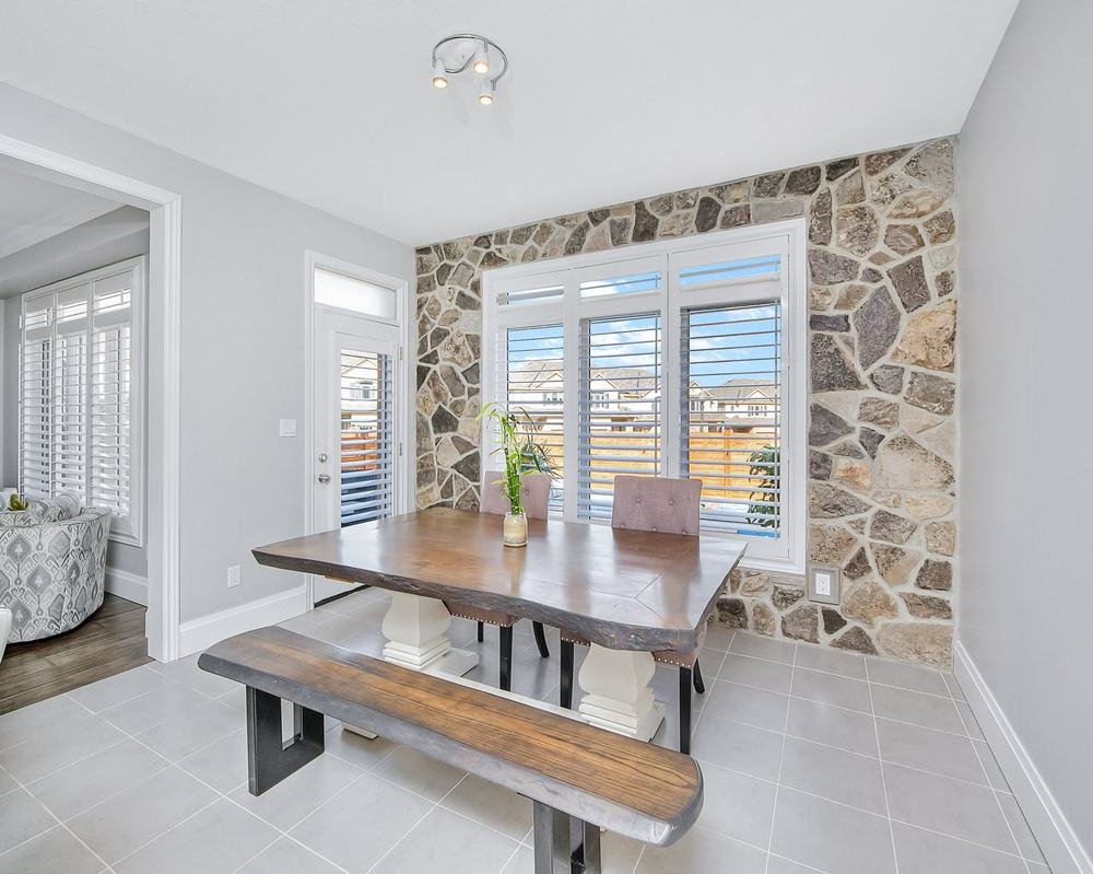 Bright dining nook with stone accent wall, tiled floor, and wood table