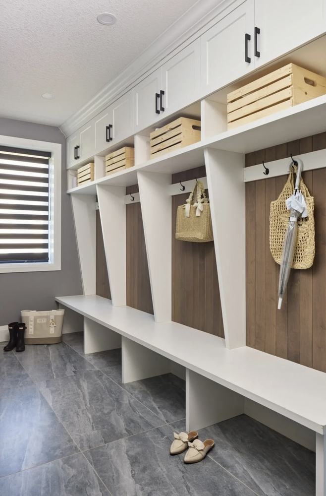 Finished mudroom with white and wood locker cabinetry and tiled floor