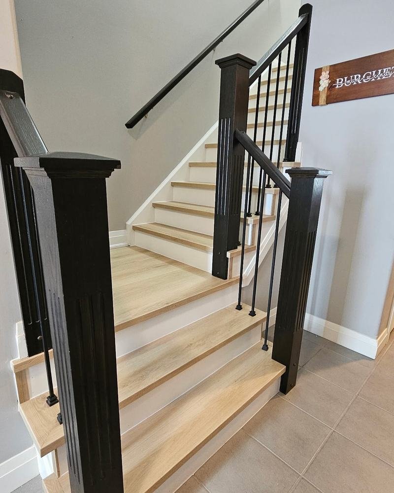 Pale wood staircase with dark posts and metal balusters