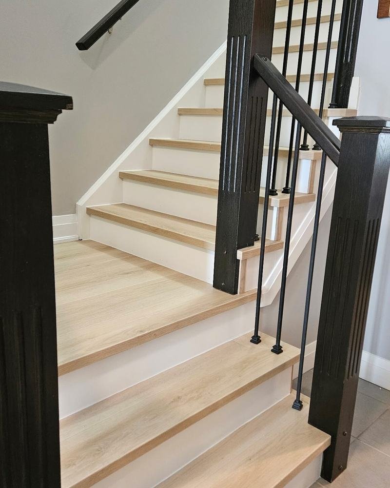 Close view of pale wood stair treads with dark railing and posts