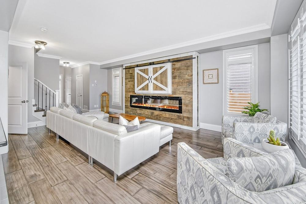 Bright open living room with a stone fireplace wall and white furnishings