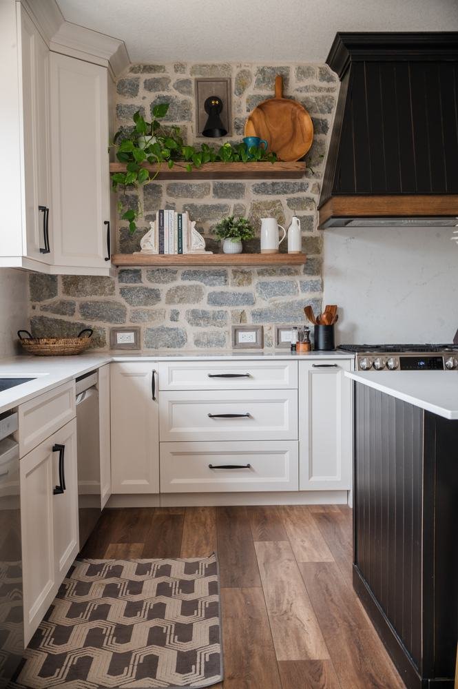 Bright kitchen corner with white and dark cabinetry against a stone feature wall