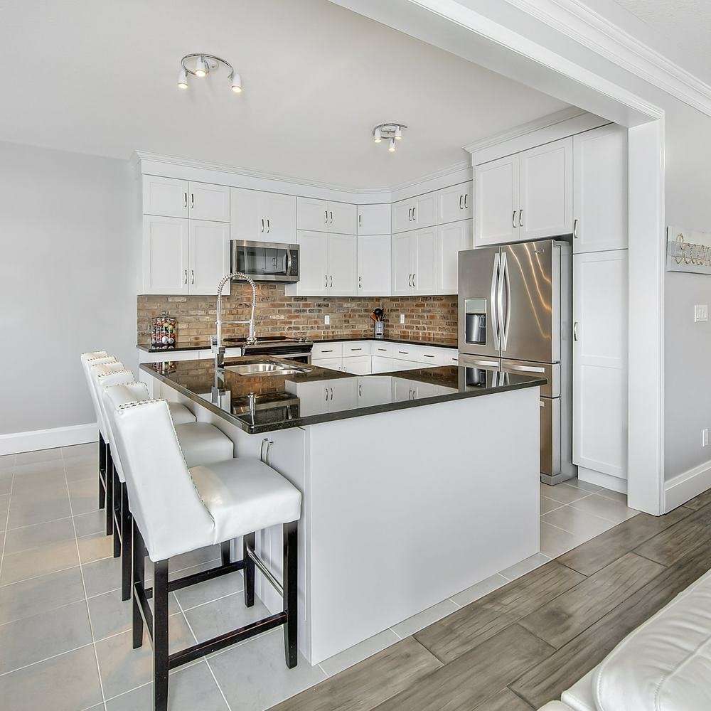 Bright white kitchen with island seating and brick-pattern backsplash
