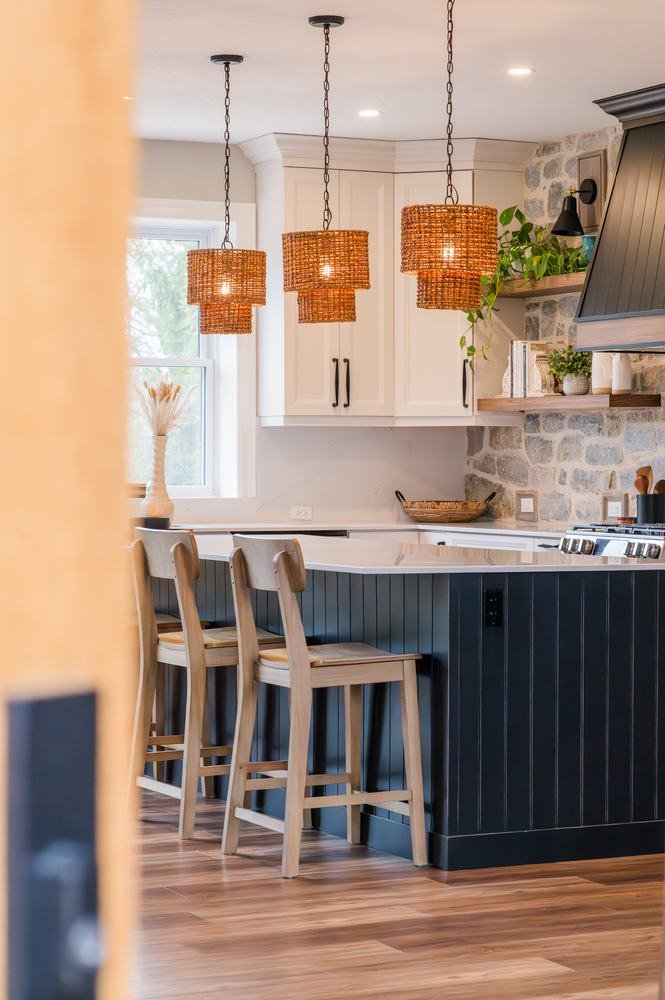Kitchen island with woven pendant lights and stone display shelves beyond
