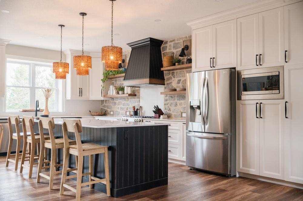 Bright white kitchen with dark island, stone backsplash, and pendant lighting