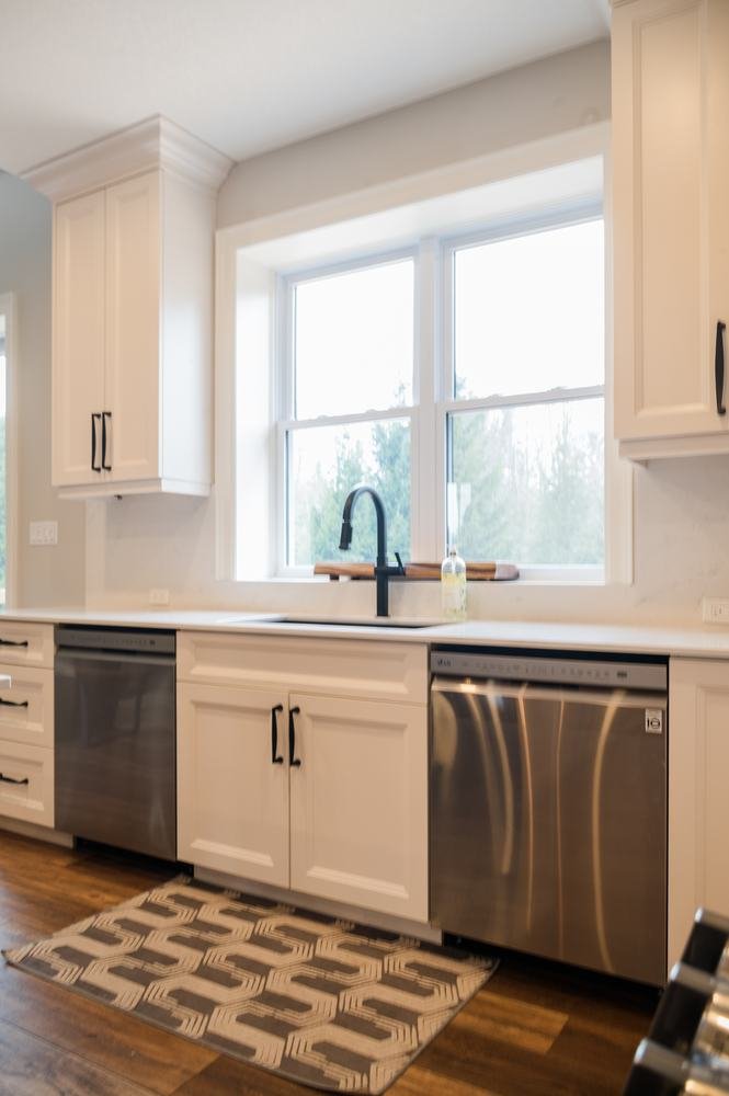 White kitchen sink wall with dark faucet and stainless dishwasher