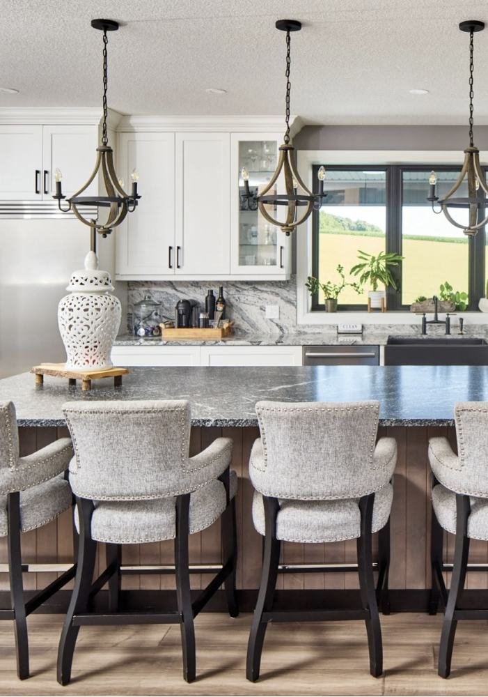Large kitchen island with four stools, white cabinetry, and pendant lighting