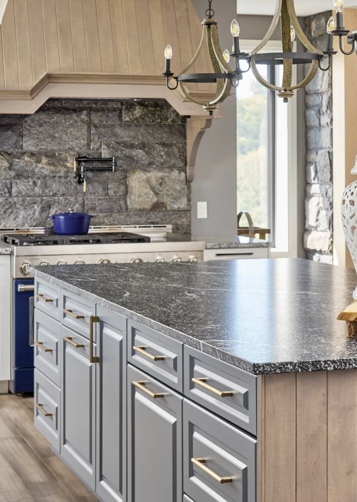 Kitchen island and cabinetry with stone range surround visible beyond