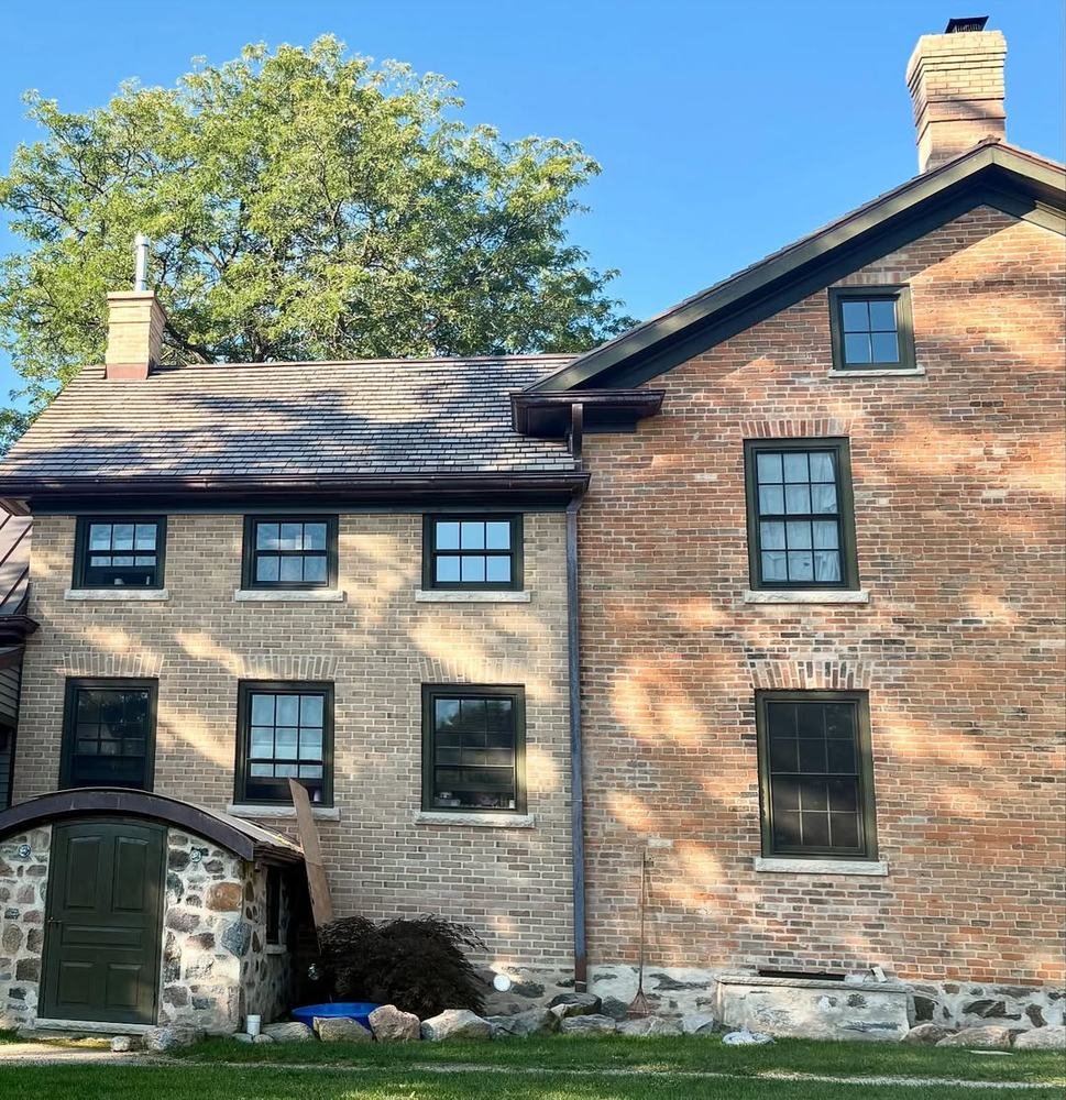 Restored older brick building with stone base and dark-framed windows