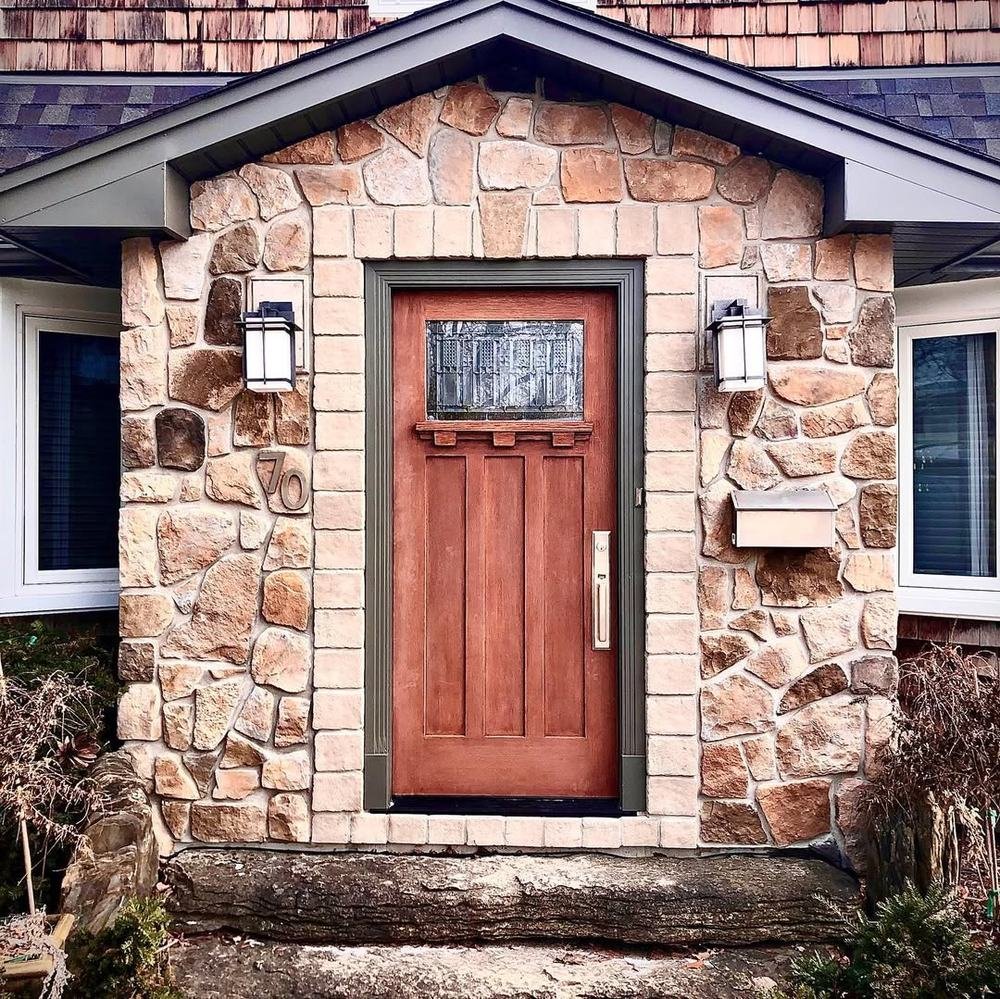 Front doorway framed by warm-toned natural stone and exterior lights