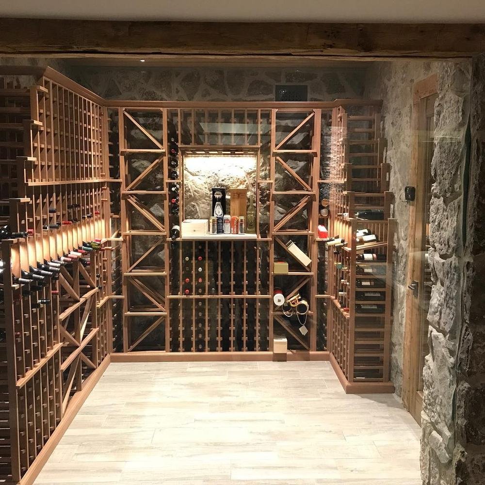 Stone-walled wine cellar with extensive wood racks and a bright central aisle